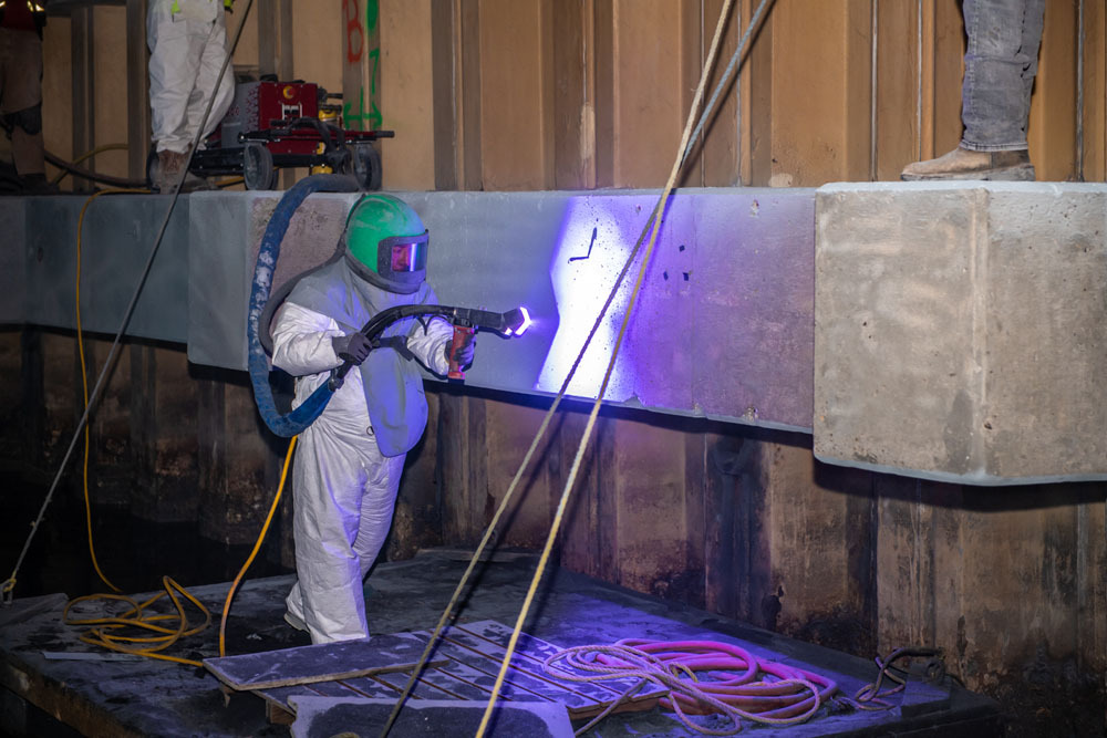 An image of a epoxy Design Systems structural concrete repair specialist holding a blue light to a concrete structural repair job he is completing